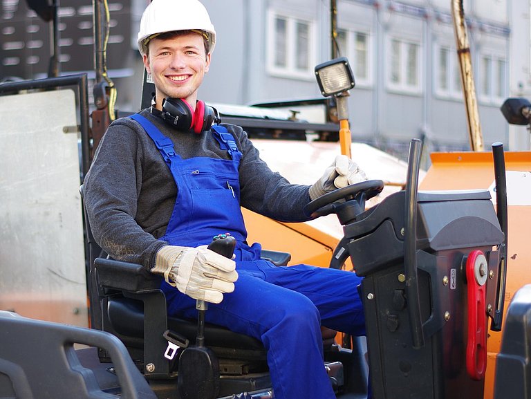 lächelnder Mann auf einer Straßenbaumaschine